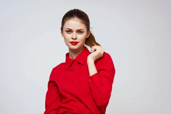 A beautiful girl with red lips and a shirt on a light background gestures with her hands — Stock Photo, Image