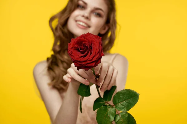 Chica romántica sobre un fondo amarillo con una flor roja en la mano y un modelo de vestido de noche —  Fotos de Stock