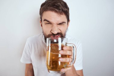 Büyük bir bardak birayla duygusal bir adam alkollü içki içiyor ve sarhoş halde el kol hareketi yapıyor.