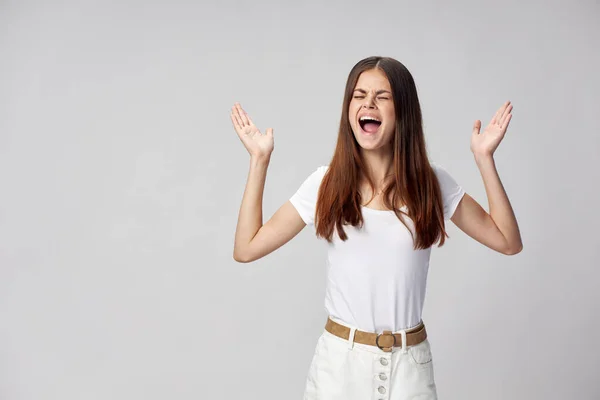 Емоційна дівчина в білій футболці і в шортах жести своїми руками з широкого відкритого рота — стокове фото