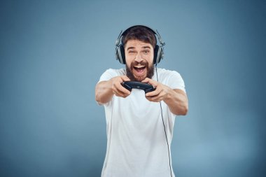 Kulaklıklı bir adam elinde oyun konsolu yaşam tarzı duyguları oynuyor mavi arka plan beyaz tişörtü