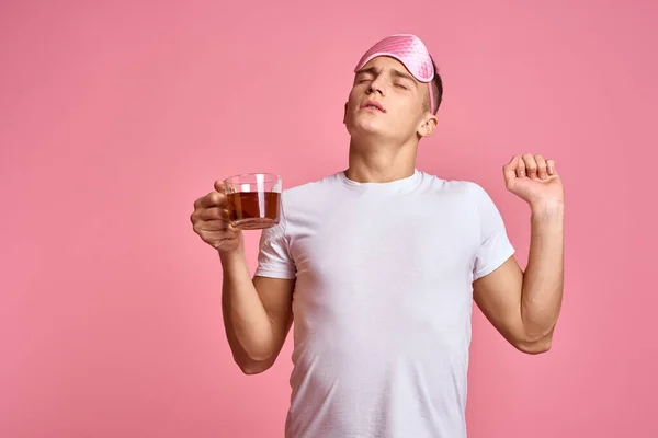 Un homme avec une boisson chaude et une tasse de thé masque rose pour un sommeil matinal vigoureux — Photo