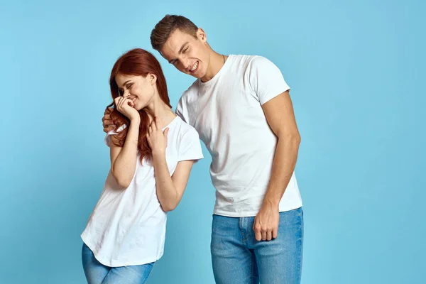 Retrato de uma menina e um cara em um fundo azul em camisetas brancas e jeans vista cortada de amigos — Fotografia de Stock