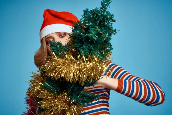 Mujer enérgica con las manos del árbol de navidad ramas del árbol modelo sombrero rojo año nuevo —  Fotos de Stock