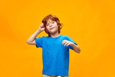 Mavi tişörtlü kızıl saçlı çocuk çocukluğunda elini başının üstünde tutuyordu. 