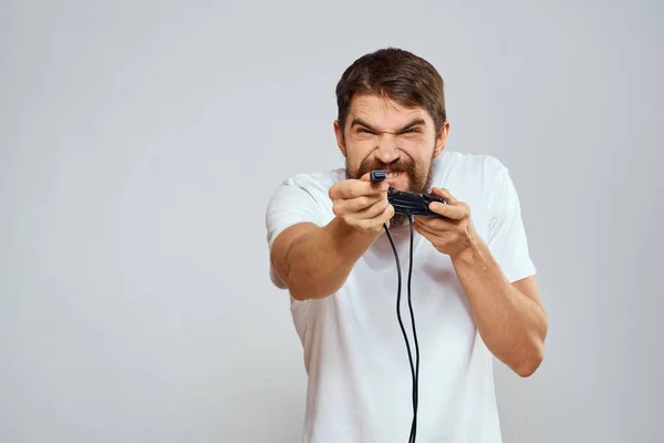 Un hombre con un mando en sus manos jugando juegos ocio estilo de vida tecnología blanco camiseta fondo claro —  Fotos de Stock