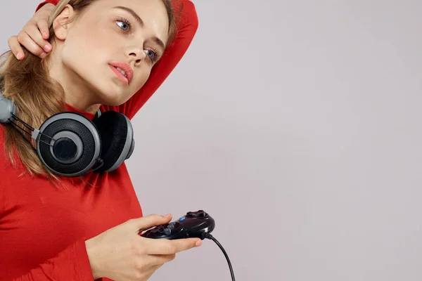 Mujer con auriculares controlador en las manos un juego de consola divertido ocio chaqueta roja estilo de vida luz fondo — Foto de Stock