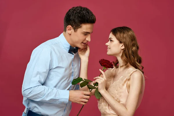 Portrét romantického páru v lásce s červenou růží na izolovaném pozadí a klasické oblek večerní šaty — Stock fotografie