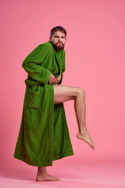 Um homem emocional em um manto verde em pleno crescimento em um fundo rosa gestos com as mãos para o modelo — Fotografia de Stock