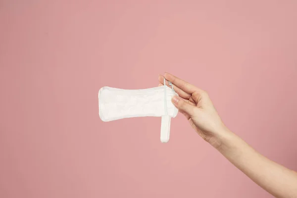 Almofada protetora e tampão em mãos femininas em um fundo rosa menstruação dias críticos — Fotografia de Stock