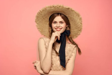 Şapkalı ve siyah kurdeleli güzel bir kadın. Pembe arka plan modeli.