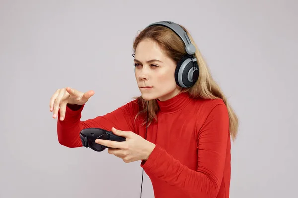Kulaklıklı bir kadın elinde Joystick ile oyun oynuyor eğlence amaçlı eğlence amaçlı yaşam tarzı kırmızı gömlek gri arka plan — Stok fotoğraf
