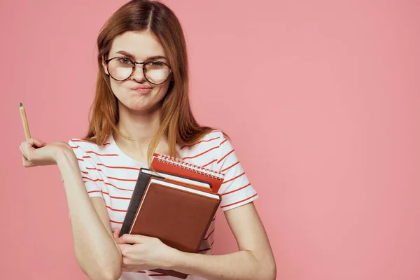 Mladá studentka s knihami na růžovém pozadí brýle na tváři vzdělávání ústav oříznutý pohled — Stock fotografie