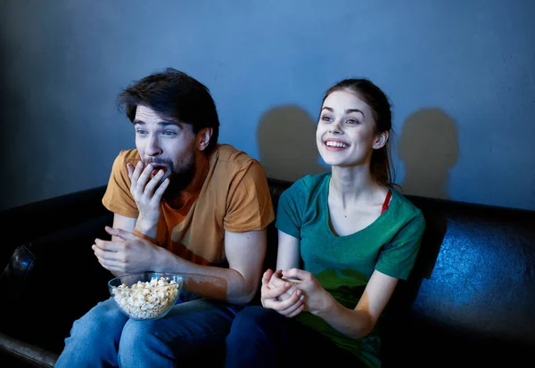 Наляканий чоловік і щаслива жінка дивиться телевізор увечері на дивані — стокове фото