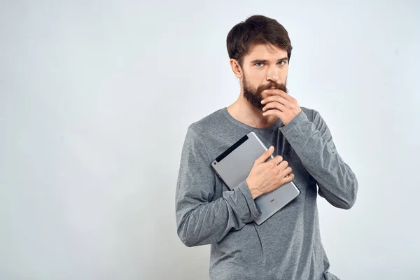 Чоловік у сірому светрі, який тримає таблетку в руках емоцій Інтернет - технології життя на світлому тлі. — стокове фото