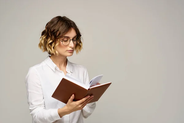 Femme avec bloc-notes dans les mains travail d'affaires beige fond lunettes coiffure — Photo