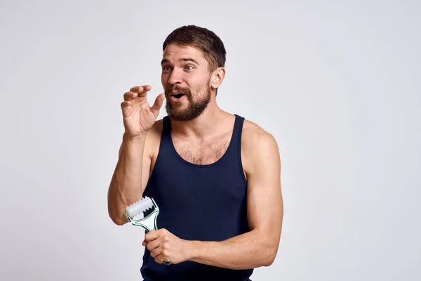 Uomo con un massaggiatore in mano e in una t-shirt blu trattamenti benessere igiene pelle pulita emozioni modello — Foto Stock