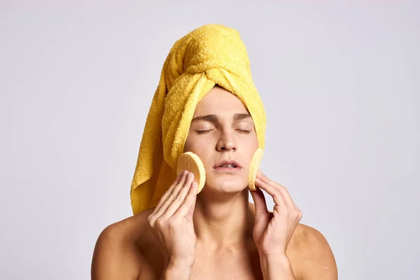 Beau homme avec une éponge faciale de cosmétologie et une serviette jaune sur la tête — Photo