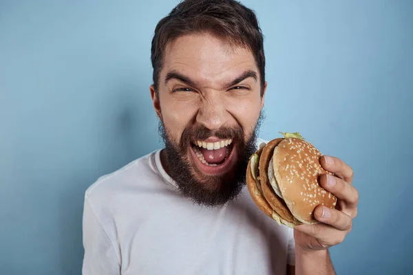Hamburguesa hombre emocional comida rápida dieta primer plano fondo azul — Foto de Stock