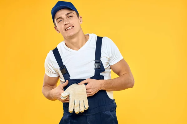 Trabalhador em uniforme de luvas prestando serviço de fundo amarelo — Fotografia de Stock