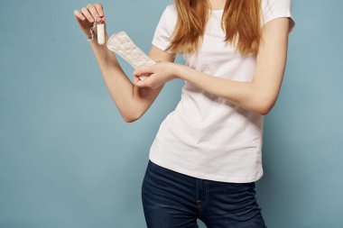 Elinde tampon ve yastıkla mavi arka plan hijyen temizliği regl olmuş bir kız.