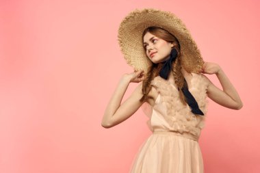 Şapkalı ve siyah kurdeleli güzel bir kadın. Pembe arka plan modeli.