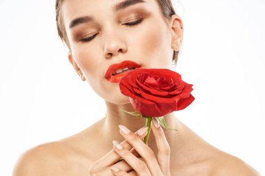 Yüzü makyajlı ve elinde kırmızı bir gül olan çekici esmer kız.