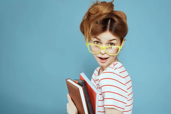 Energieke vrouwelijke student met notitieblokken en bril model blauwe achtergrond — Stockfoto