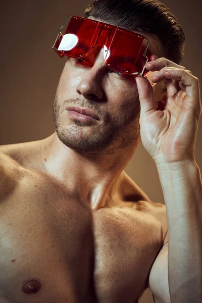 Un gars avec des muscles pompés dans ses bras redresse les lunettes sur son visage gros plan — Photo