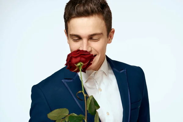 Un homme en costume avec une rose dans ses mains un cadeau date fond clair — Photo