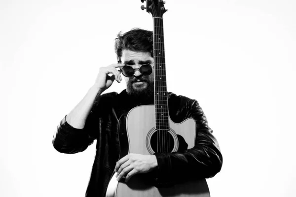 Un homme tient une guitare dans ses mains musique émotions cuir noir veste noir lunettes studio lumière arrière-plan — Photo