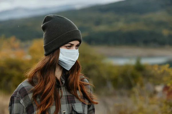 Kobiety w jesiennym lesie spoglądają w bok i mają maskę medyczną na twarzy. — Zdjęcie stockowe