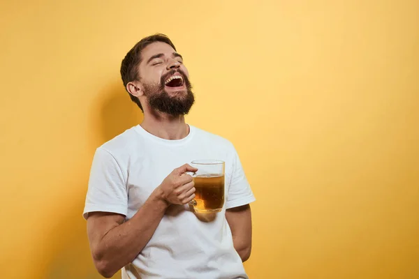 Чоловік з чашкою пива веселий алкогольний спосіб життя біла футболка жовтий ізольований фон — стокове фото