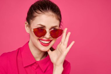 Pembe gömlekli ve kahverengi gözlüklü kadın kırpılmış görünüm modeli duyguları el hareketleriyle resim yapıyor.