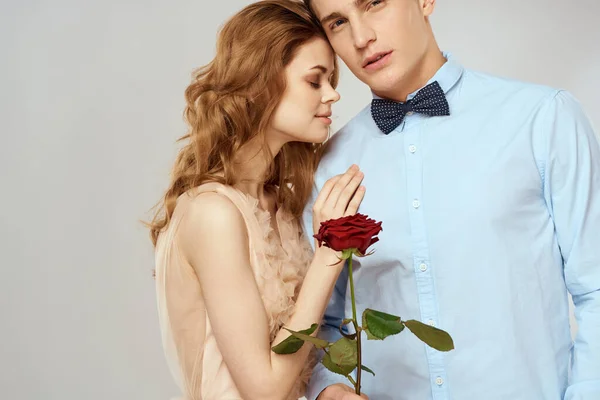 Um jovem casal amoroso com uma rosa vermelha em suas mãos em um romance fundo leve — Fotografia de Stock
