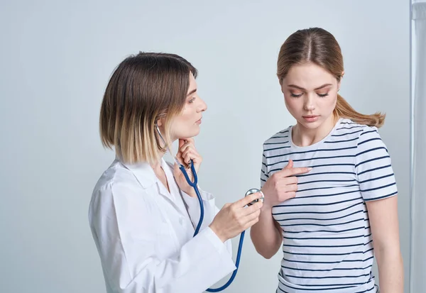 Médico mulher em vestido médico com estetoscópio escuta pacientes coração — Fotografia de Stock