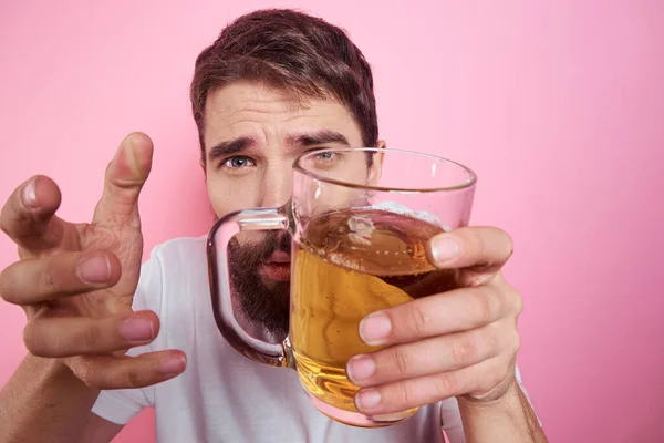 Homme ivre avec une grande tasse de bière Sur un fond rose et un T-shirt blanc vue détendue d'une barbe épaisse — Photo