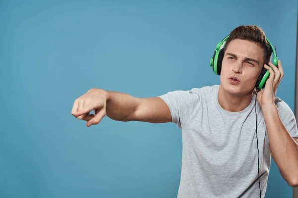 Man met groene hoofdtelefoon luistert naar muziek entertainment lifestyle wit t-shirt blauwe achtergrond — Stockfoto