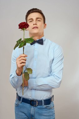 Kırmızı gül ve açık renk pantolon giyen romantik bir adam.