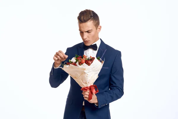 En elegant man i klassisk kostym med fluga håller en bukett blommor i handen — Stockfoto