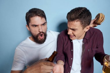 İki neşeli sarhoş arkadaş mavi bir arka planda bira içiyorlar.