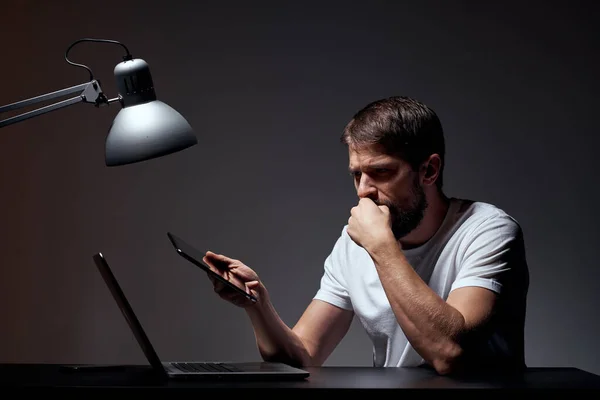 Hombre con portátil sentado en la mesa fondo oscuro lugar de trabajo oficina emociones lámpara gesto con las manos modelo vista recortada —  Fotos de Stock