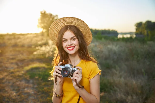 Wanita ceria memegang kamera di tangannya bibir merah tersenyum di sebuah topi luar — Stok Foto