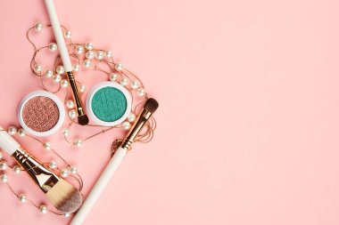 Göz falı aksesuarlar, boncuklar makyaj fırçaları pembe arka planda profesyonel kozmetik ürünleri koleksiyonu.