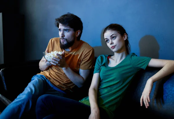 Mujer emocional y el hombre con un plato de palomitas de maíz viendo la televisión en el interior de la noche — Foto de Stock