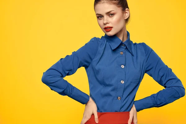 Attractive woman in blue shirt gesturing with her hands and red skirt yellow background portrait cropped view — Stock Photo, Image
