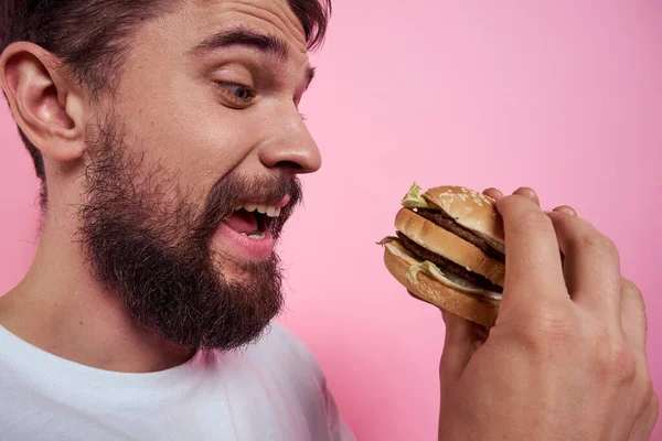 Portrét muže s hamburgerem na růžovém pozadí zblízka oříznutý pohled na model — Stock fotografie