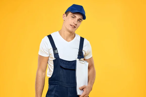 Hombre en documentos uniformes de trabajo prestación de servicios servicio de entrega fondo amarillo — Foto de Stock