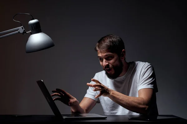 Homem com laptop sentado à mesa fundo escuro no local de trabalho emoções do escritório lâmpada gestual com as mãos modelo corte vista — Fotografia de Stock