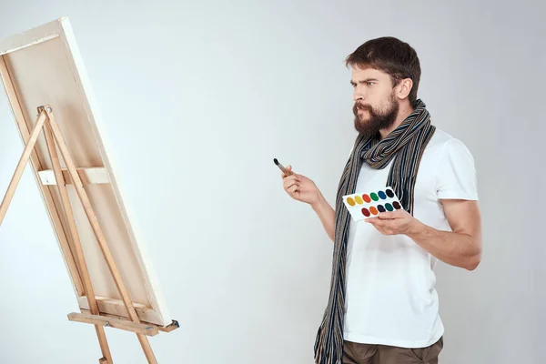남자 미술가가 이젤 붓에 그림을 그리고 취미 창의력의 빛을 이용 해 손에 그림을 그립니다 — 스톡 사진